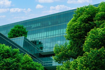 Eco-friendly building in the modern city. Sustainable glass office building with trees for reducing...