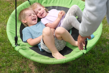 Grandfather swinging children in summer park. Grand dad and grandchildren sitting on swing...