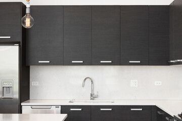 A kitchen sink detail in a modern kitchen with dark wood cabinets, marble countertop and...