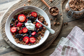 A mixed berry and granola cluster breakfast bowl topped with greek yogurt.