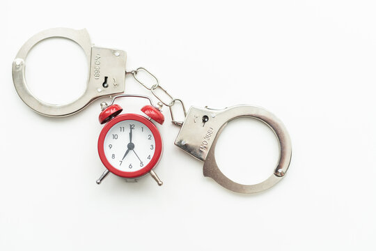 Gray Metal Handcuffs With Clock On Isolated Muted Pastel Blue Background. Business Abstract Concept. Minimal Flat Lay. The Idea Of A Lack Of Time, A Deadline Or Being Trapped In Time.