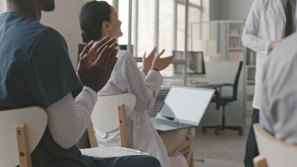 Cropped shot of team of doctors applauding to speaker after his presentation at medical conference