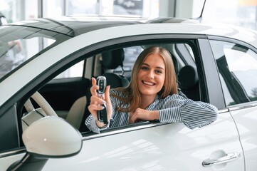 New owner of the car. With keys in hands. Beautiful woman is indoors