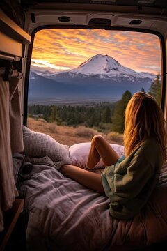 Young woman relaxed in a van looking a gorgeous sunset landscape. hippie and camper van life concept.