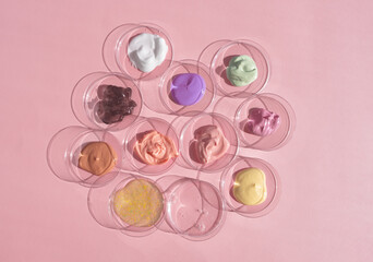 Multicolored textures of cream, scrub, serum and gel in Petri dishes on a pink background. Concept of cosmetics laboratory researches. Smear of skincare cosmetics product. Wellness and beauty concept.