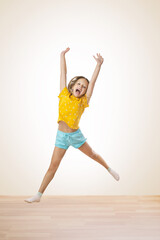  portrait of a little girl jumping while on a white background in a studio. happy joyful kid girl...
