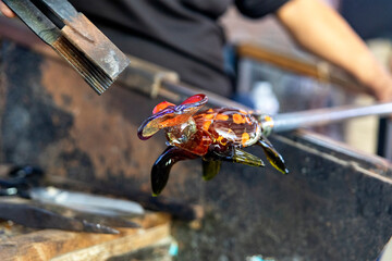 Craftsman working, cutting, molding and creating a glass turtle with the traditional method of...