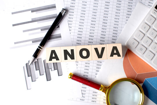 ANOVA text on wooden block on graph background with pen and magnifier