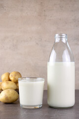 Vegan potato milk and potatoes on a brown background. Plant-based lactose-free milk. Vegetable milk. 