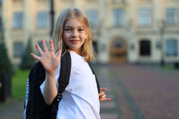 Fototapeta premium Smiling positive girl waving, back to school.