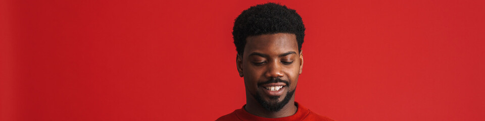 Black bearded young man smiling and using cellphone