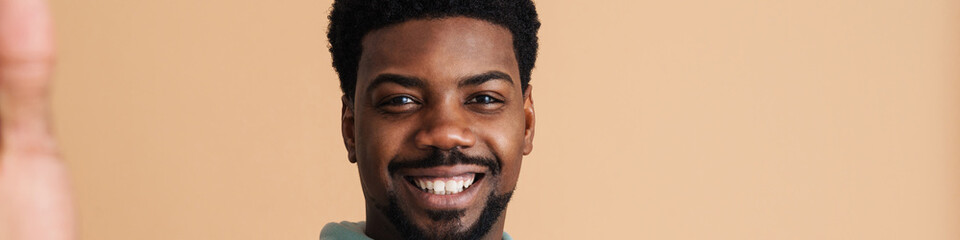 Obraz premium Black bearded young man smiling and taking selfie photo