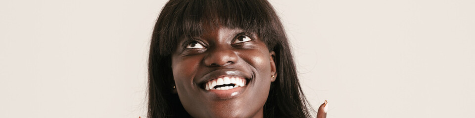 Fototapeta premium Young beautiful smiling african woman with bob haircut pointing up