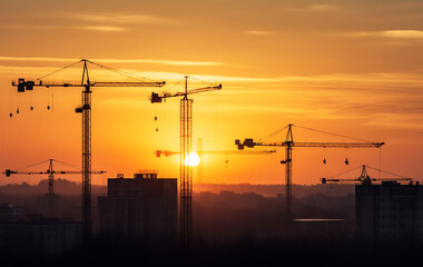 Construction cranes silhouette with sunset in the background. Generative AI.