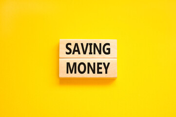 Saving money symbol. Concept words Saving money on wooden blocks on a beautiful yellow table yellow background. Business, support and saving money concept. Copy space.
