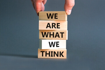 We are what we think symbol. Concept word We are what we think on wooden block. Beautiful grey table grey background. Businessman hand. Business We are what we think concept. Copy space.