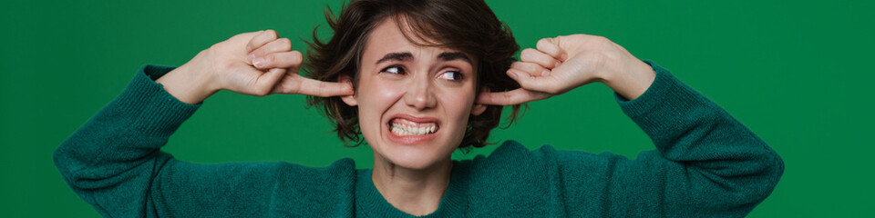 Young displeased woman frowning while plugging her ears