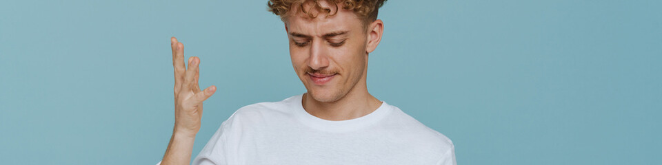 Obraz premium Young handsome curly thoughtful man with mustache with raised hand