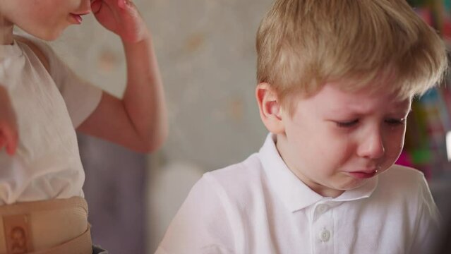 Little boy cries and careful sister calms him down at home