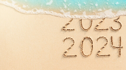 New Year concept banner of coming 2024. Numbers 2023 handwritten in sand, tropical beach background...
