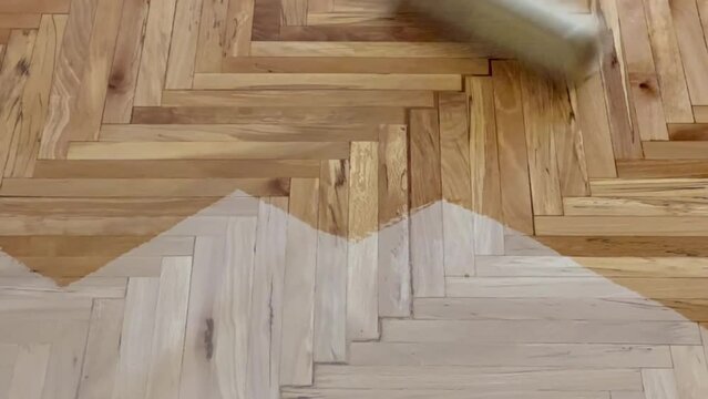 A worker is applying a scraper polish to a parquet that has deteriorated.