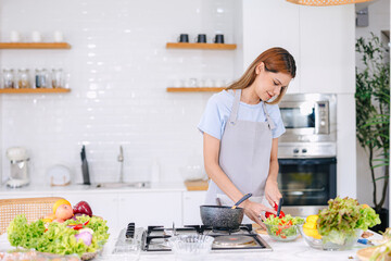 beautiful young woman trying cook healthy food salad vegetables mix at home kitchen