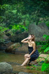Beautiful Woman asia slim fitness model posing sexy in creeks wearing Sarong shower and wash a clothes in the stream from the waterfall to show the lifestyle of people in the countryside with nature