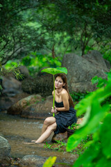 Beautiful Woman asia slim fitness model posing sexy in creeks wearing Sarong shower and wash a clothes in the stream from the waterfall to show the lifestyle of people in the countryside with nature