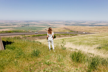 Beautiful summer landscape with meadows and a road from a bird's eye view. Nature in Oregon. A girl in sportswear with red hair walks in a summer meadow, rests in nature, admires nature