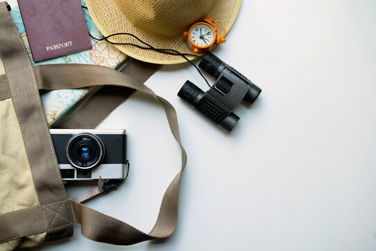 Top view of accessories for tourist to travel in Brown tone on Travel concept, Camera on notebook and airplane with passport and watch and hat with wallet  on wooden background.