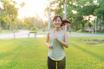 Fit Asian young woman jogging in park smiling happy running and enjoying a healthy outdoor lifestyle. Female jogger. Fitness runner girl in public park. healthy lifestyle and wellness being concept