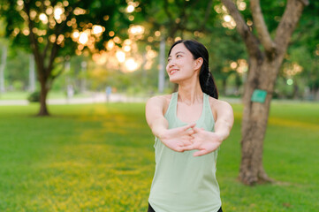 Female jogger. Fit young Asian woman with green sportswear stretching muscle in park before running and enjoying a healthy outdoor. Fitness runner girl in public park. Wellness being concept