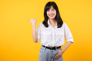 Businesswoman. young asian woman happy smile dressed in white shirt showing pointing finger hand gesture to free space isolated on a yellow background. presenting advertising advice promotion concept.