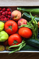 Wooden crate full of healthy seasonal fruit and vegetable. Top view, wooden background.