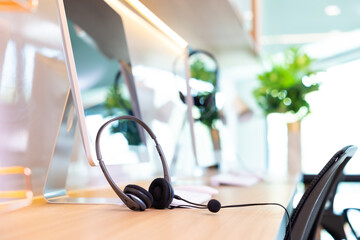 headset on desk with computer desktop at customer service and marketing support workplace. Office...