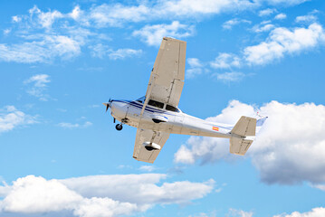 Single engine ultralight plane flying in the blue sky with white clouds