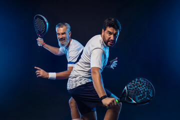 Padel tennis doubles. Two athletes players with racket. Man athlete with paddle racket on court with neon colors. Sport concept. Download a high quality photo for the design of a sports app