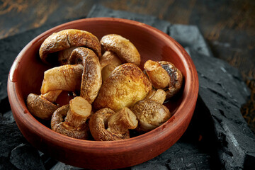 Mushrooms grilled on charcoal in a bowl on a dark background