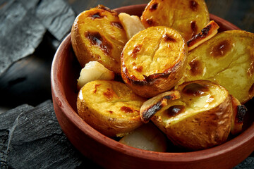 Potatoes grilled on charcoal in a bowl on a dark background