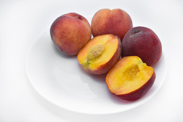 Juicy peaches on a white plate. Yellow-red large ripe peaches. Juicy fruits.