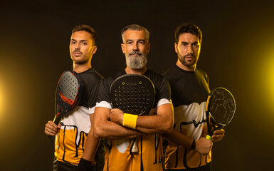 Group of padel tennis players with racket. Men athletes with paddle racket on court with neon...