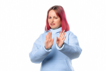 Portrait of young woman deny something, say no, rejects offer, looks insulted, express disapproval. Lovely female model with pink hair in a blue hoodie standing over white background