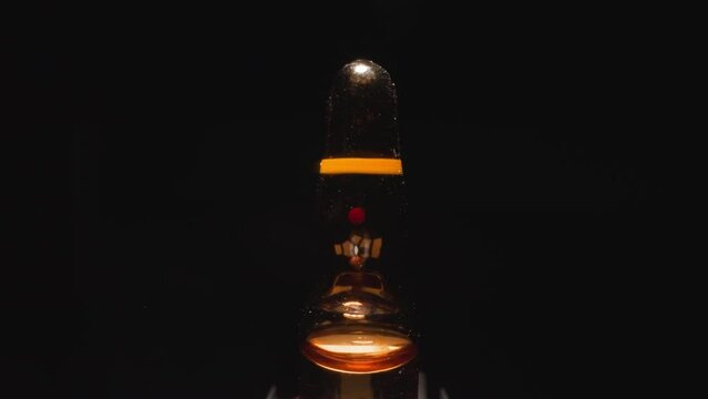 Glass ampule with brown liquid reflecting studio light
