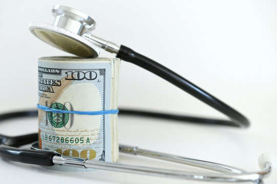 Stethoscope laying on roll of money - Medical costs, doctor's bills, cost of insurance