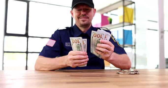 Policeman sitting at table and counting money near handcuffs 4k movie slow motion. Bribery and police corruption concept 
