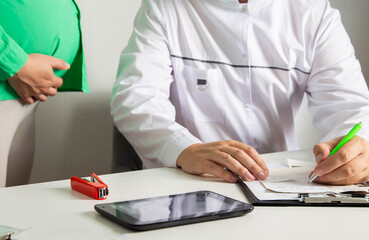 An obstetrician-gynecologist writes a direction for a pregnant girl to take hormone tests. Hormonal background of pregnant women, the hormone progesterone and estrogen. Baby health.