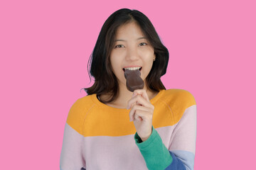 Beautiful young woman smiling happily while holding ice cream in her hand