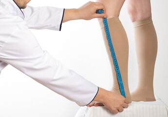 Doctor phlebologist - a vascular surgeon selects the size of the compression stockings of the...