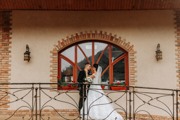 portrait of the bride and groom against the background of the window of an old authentic house, hugs and kisses. Free space. Wedding walk in the park