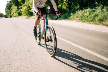 Close-up shot of male cyclist riding a professional road bike on the road outside the city.